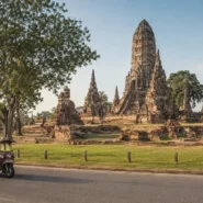 Ayutthaya frog-head tuk-tuk passing historic temple ruins in Thailand