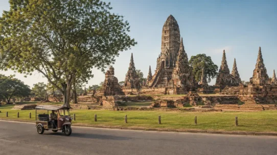 Ayutthaya frog-head tuk-tuk passing historic temple ruins in Thailand