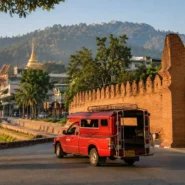 Red songthaew driving through Chiang Mai Old City, a common local transport option for travelers